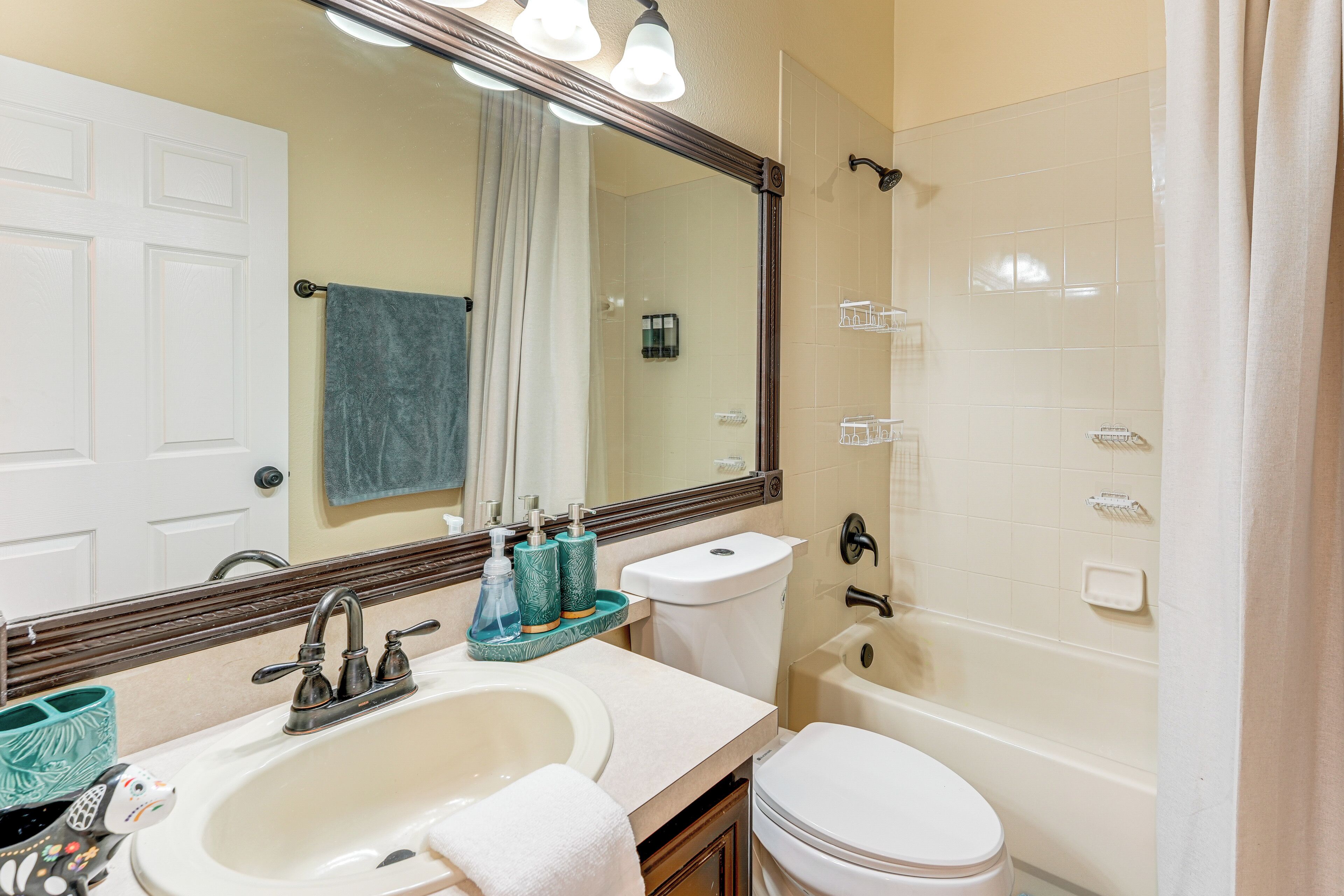 A bathroom with a sink, mirror, toilet, and bathtub.