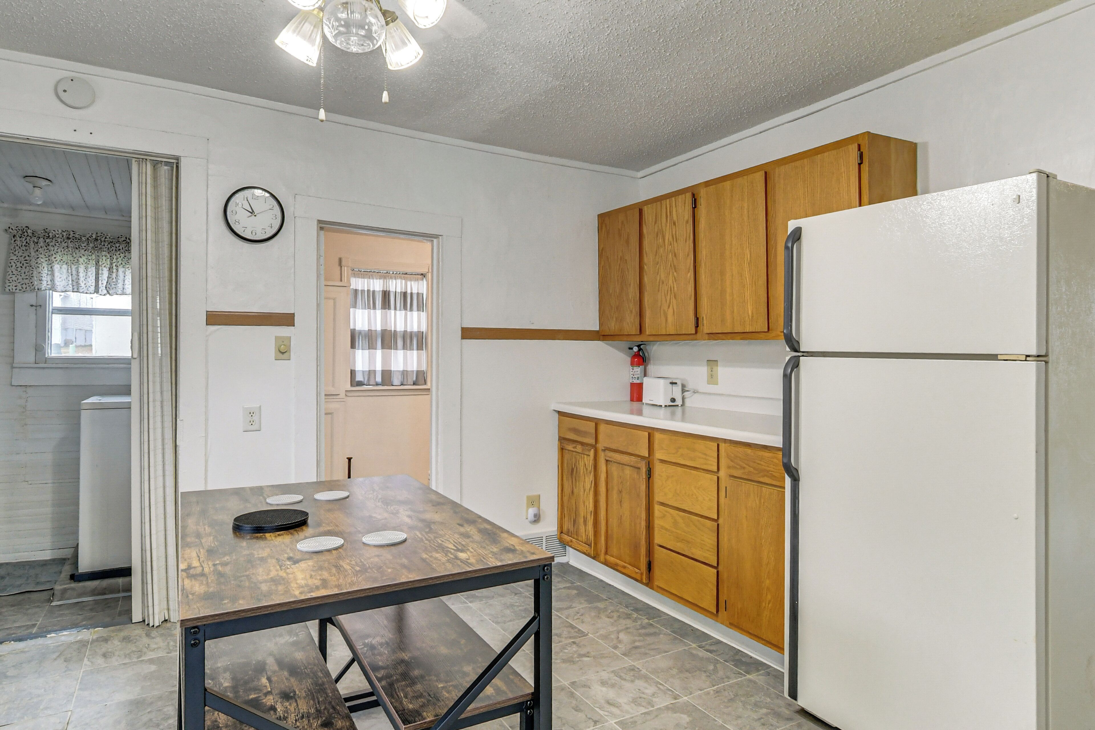 A kitchen with wooden cabinets, a white refrigerator, and a dining table with a metal frame.