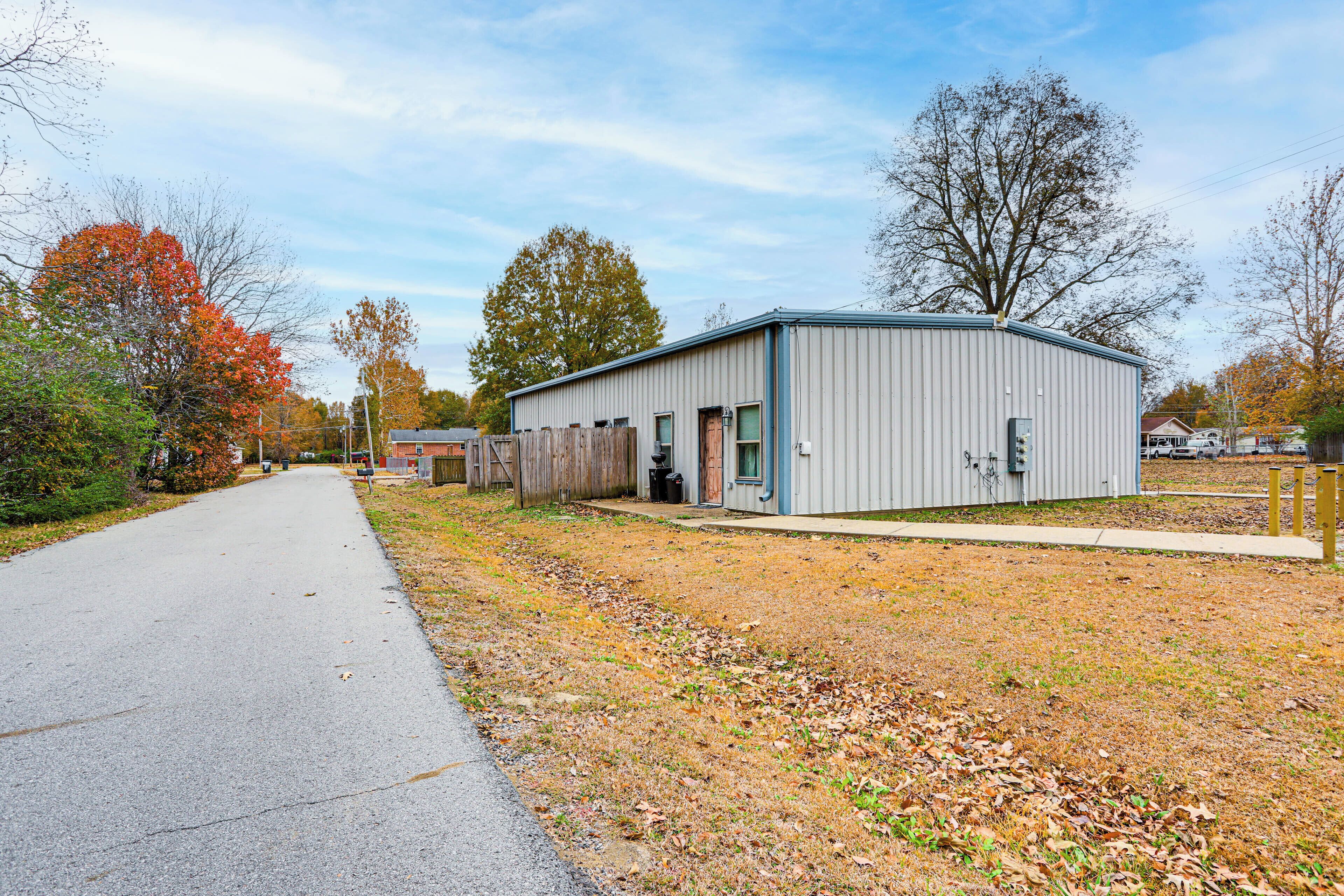 A single-story building with a flat roof, a covered outdoor area, and a paved driveway.