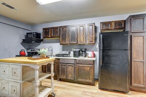 A kitchen with wooden cabinets, a black refrigerator, a microwave, and a coffee maker. - Near Universities & LR: Family Apt in Mcrae, Ark (McRae)