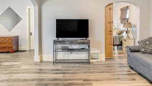 A living room with a flat-screen TV on a metal stand, a wooden dresser, and a grey sofa. - Nature Lovers Retreat By the High Trestle Trail! (Woodward)
