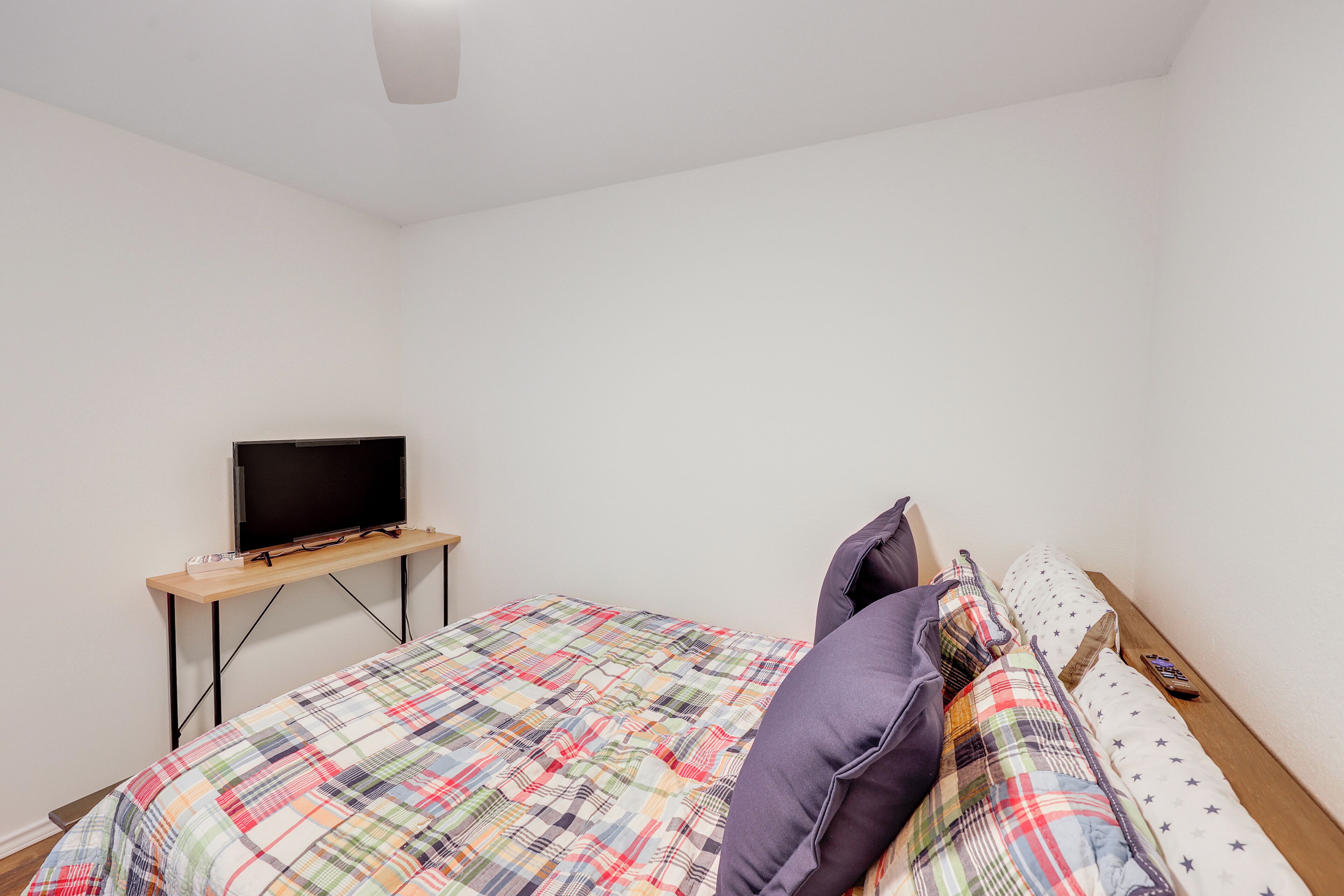 A bedroom with a bed, a TV on a stand, and a bedside table.