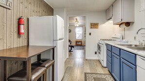 A kitchen with a wooden wall, white cabinets, a white refrigerator, and a bench. - Year-round Chain of Lakes Retreat! Northwoods Home (Eagle River)