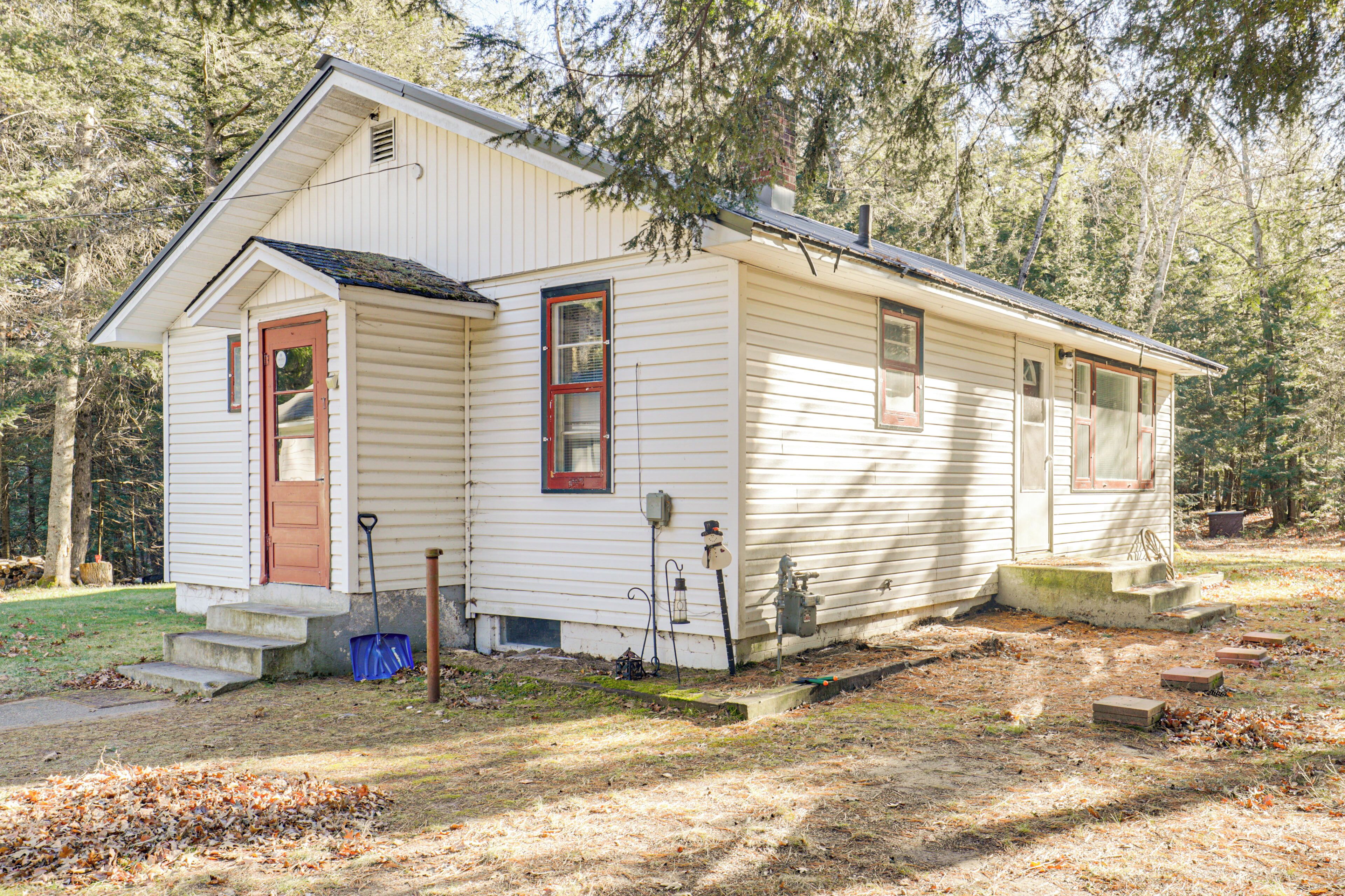 A single-story house with a front porch, a small set of steps, and a visible water spigot.