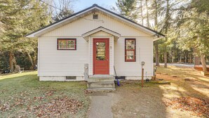 A small, single-story house with a red door and white siding, surrounded by trees. - Year-round Chain of Lakes Retreat! Northwoods Home (Eagle River)