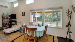 Una sala de estar con una mesa de comedor, sillas, un sofá, una estantería y un televisor.