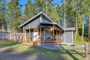 A cabin with a porch, a small deck, and a garage. - Hike & Relax Fireside: Nordland Gem w/ Deck & Yard (Nordland)