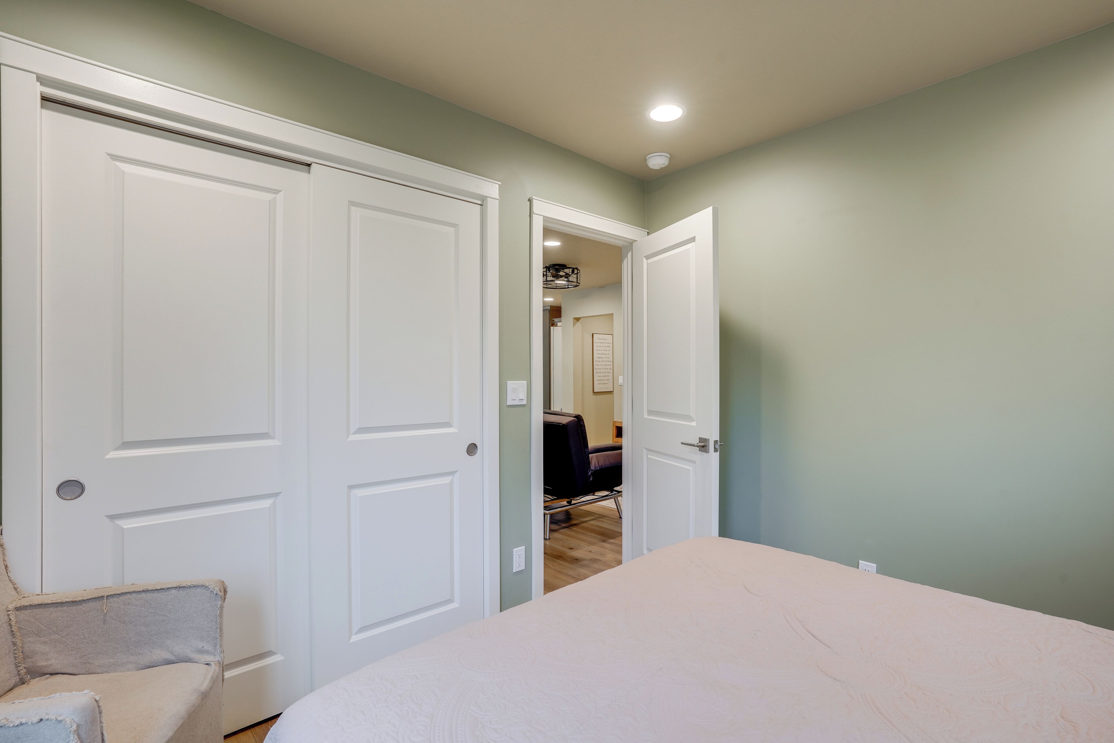 A bedroom with a bed, a chair, and a closet.