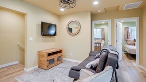 A living room with a sofa, a TV, a wooden cabinet, and a mirror. - Cozy Woodland Retreat in the Pines, Near Prescott! (Prescott)