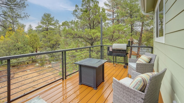 A wooden deck with outdoor furniture, a grill, and a view of trees. - Cozy Woodland Retreat in the Pines, Near Prescott! (Prescott)