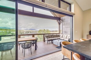A spacious balcony with a wooden deck, a cushioned seating area, and a dining table. - Luxe Home w/ Hot Tub and Views in Winter Park! (Winter Park)
