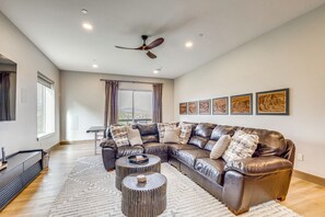 A spacious living room with a large L-shaped leather sofa, a round coffee table, and a ceiling fan. - Luxe Home w/ Hot Tub and Views in Winter Park! (Winter Park)