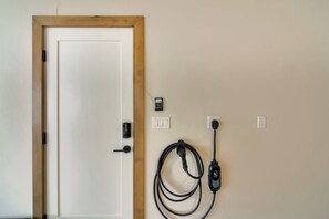 A door with a wooden frame, a wall-mounted electrical outlet, and a charging station with a cable. - Luxe Home w/ Hot Tub and Views in Winter Park! (Winter Park)