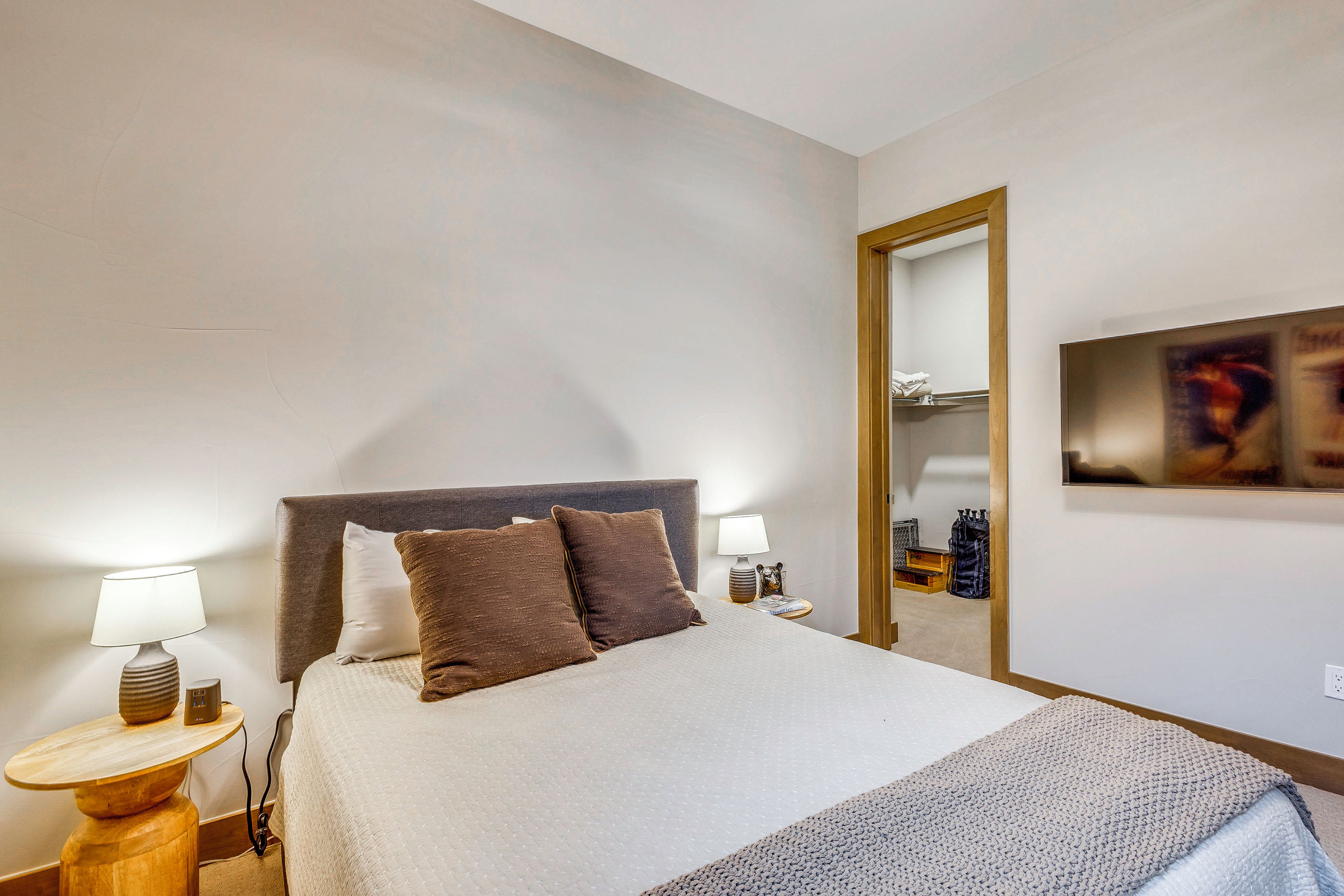 Une chambre d’hôtel comprenant un lit, deux tables de chevet, un miroir et une œuvre d’art accrochée au mur.