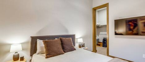 Une chambre d’hôtel comprenant un lit, deux tables de chevet, un miroir et une œuvre d’art accrochée au mur.