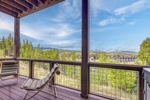 A wooden deck with a view of a forest and mountains. There are wicker chairs and a metal railing. - Luxe Home w/ Hot Tub and Views in Winter Park! (Winter Park)
