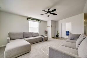 A living room with a sectional sofa, a smaller sofa, a ceiling fan, and a window with blinds. - Explore Temecula Wine Country! Mtn-view Home (Wildomar)