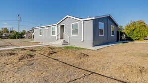 A single-story, gray mobile home with a front porch and a small staircase. - Explore Temecula Wine Country! Mtn-view Home (Wildomar)