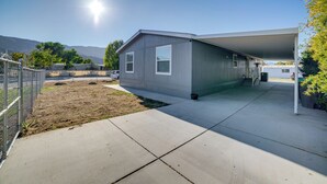 A single-story building with a covered porch, a fenced yard, and a clear sky. - Explore Temecula Wine Country! Mtn-view Home (Wildomar)