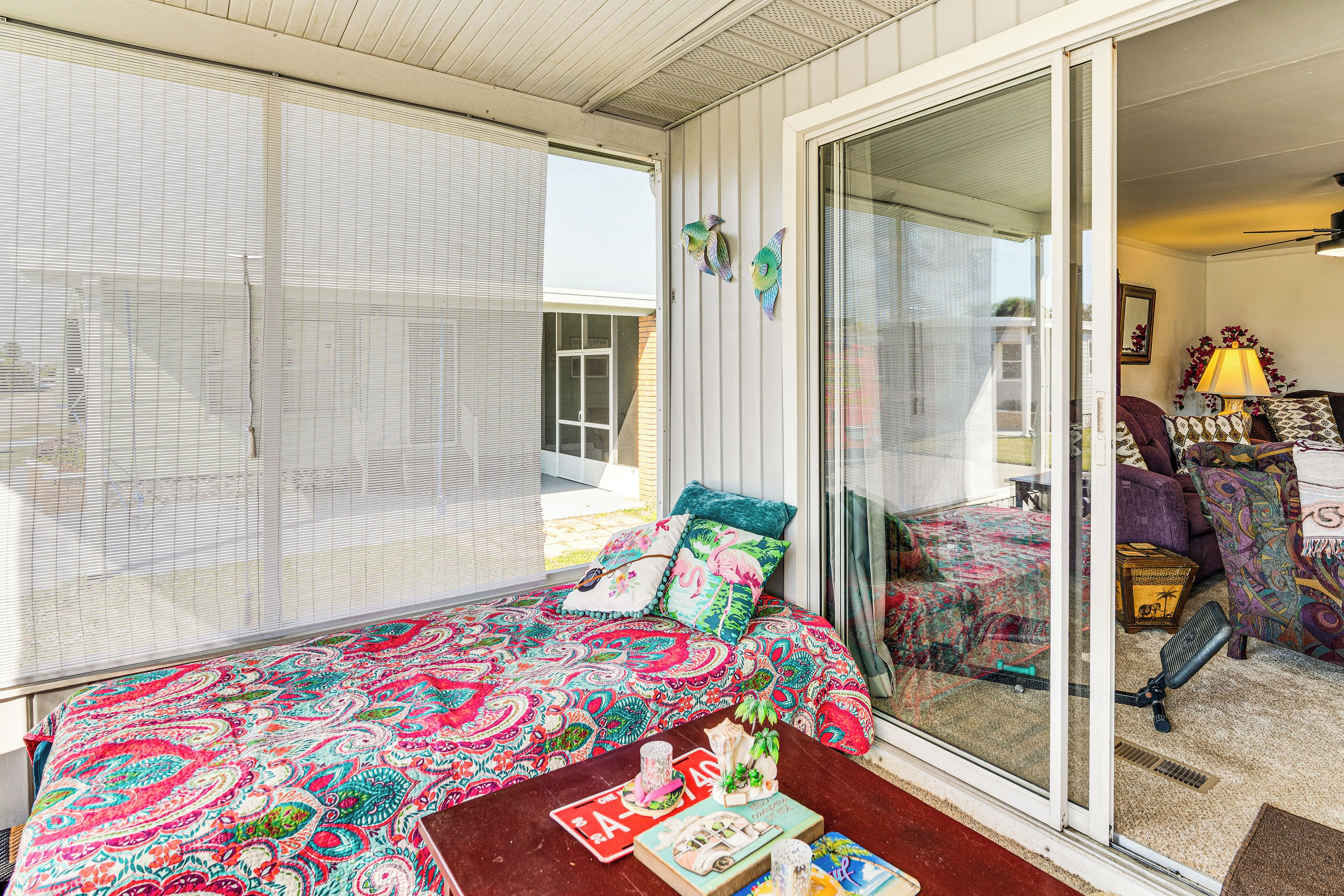 A room with a bed, a table with books, and a sliding glass door leading to another room.