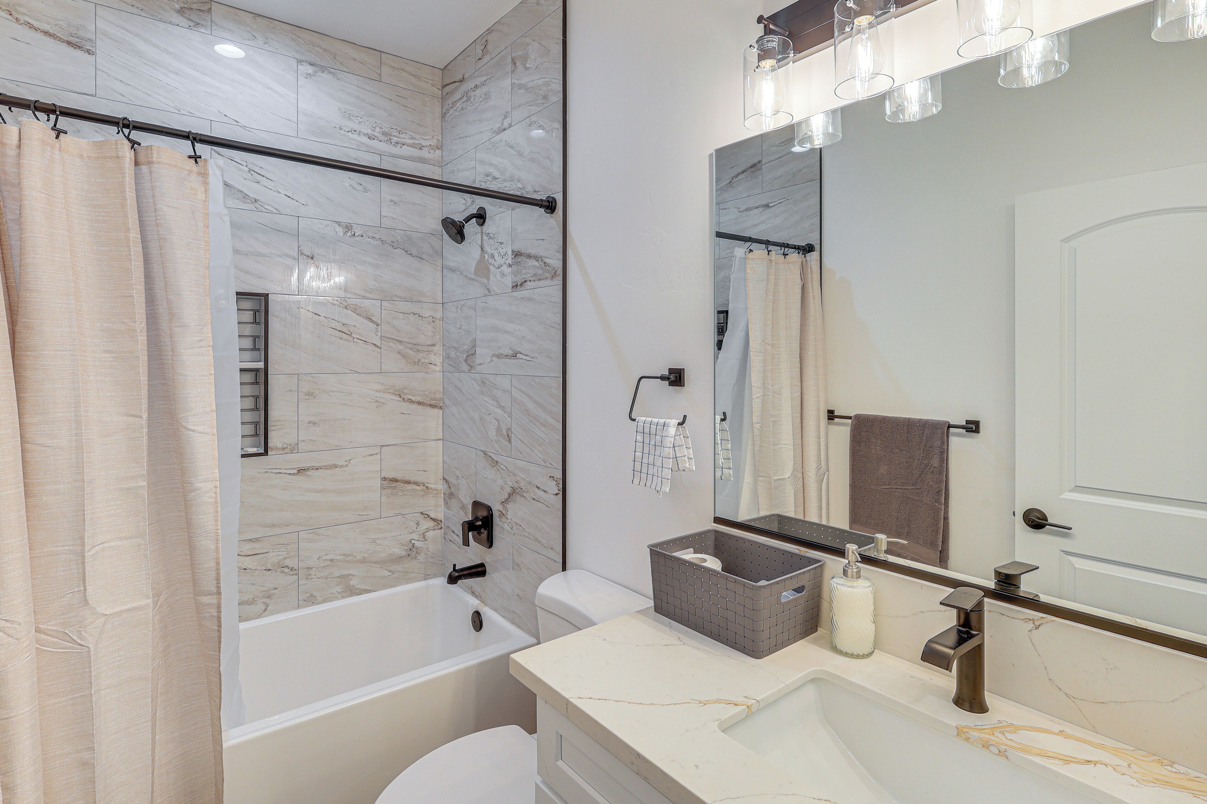 Un bagno moderno con una vasca, una doccia, un water, un lavandino e uno specchio.