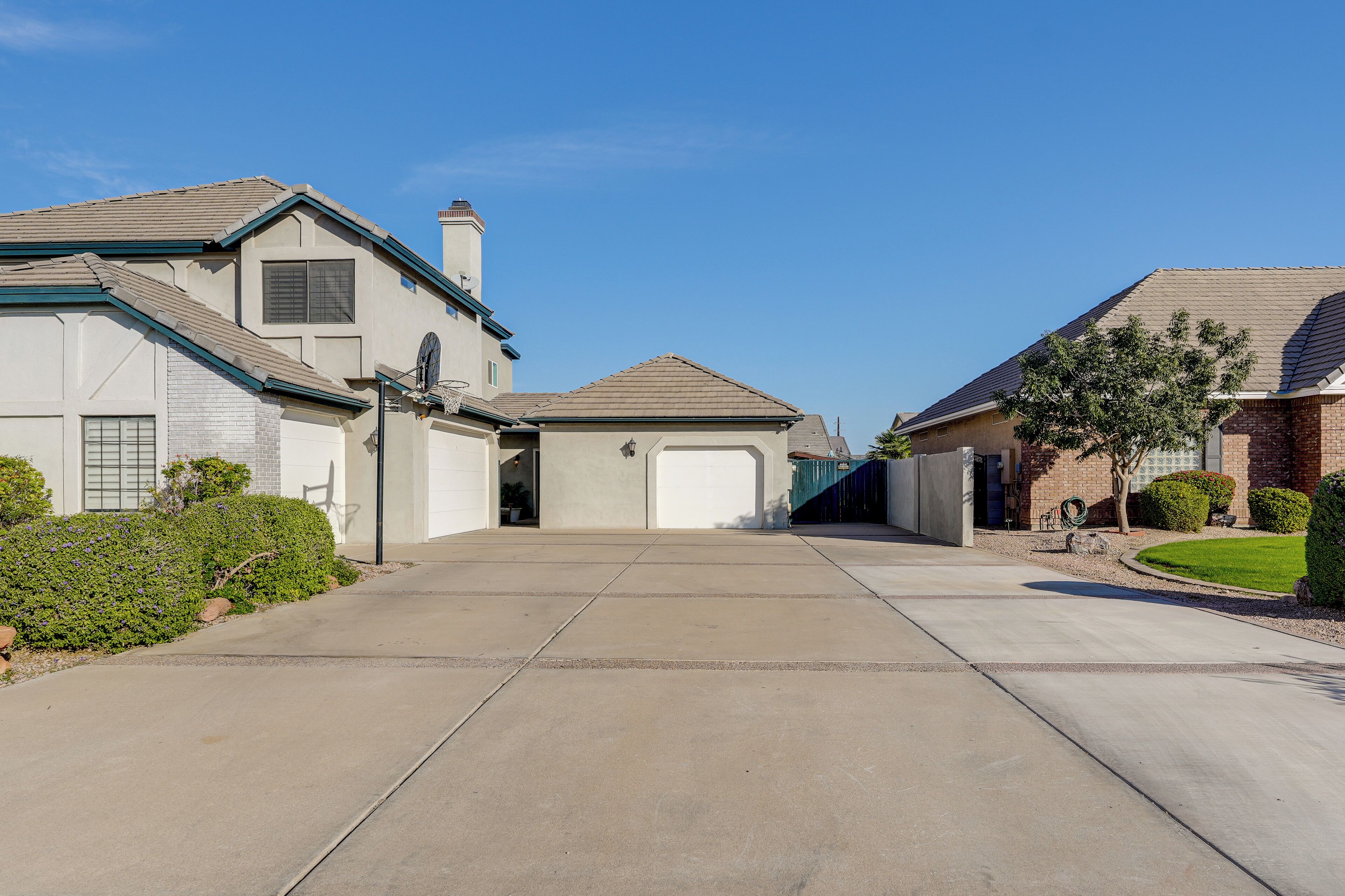 A residential driveway leading to a house with a garage, surrounded by well-maintained lawns and hedges.