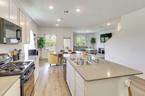 A modern kitchen with a central island, built-in appliances, and a dining area with chairs and a table. - 6 Mi to Mckinney Falls: Spacious Home w/ Game Room (Austin)