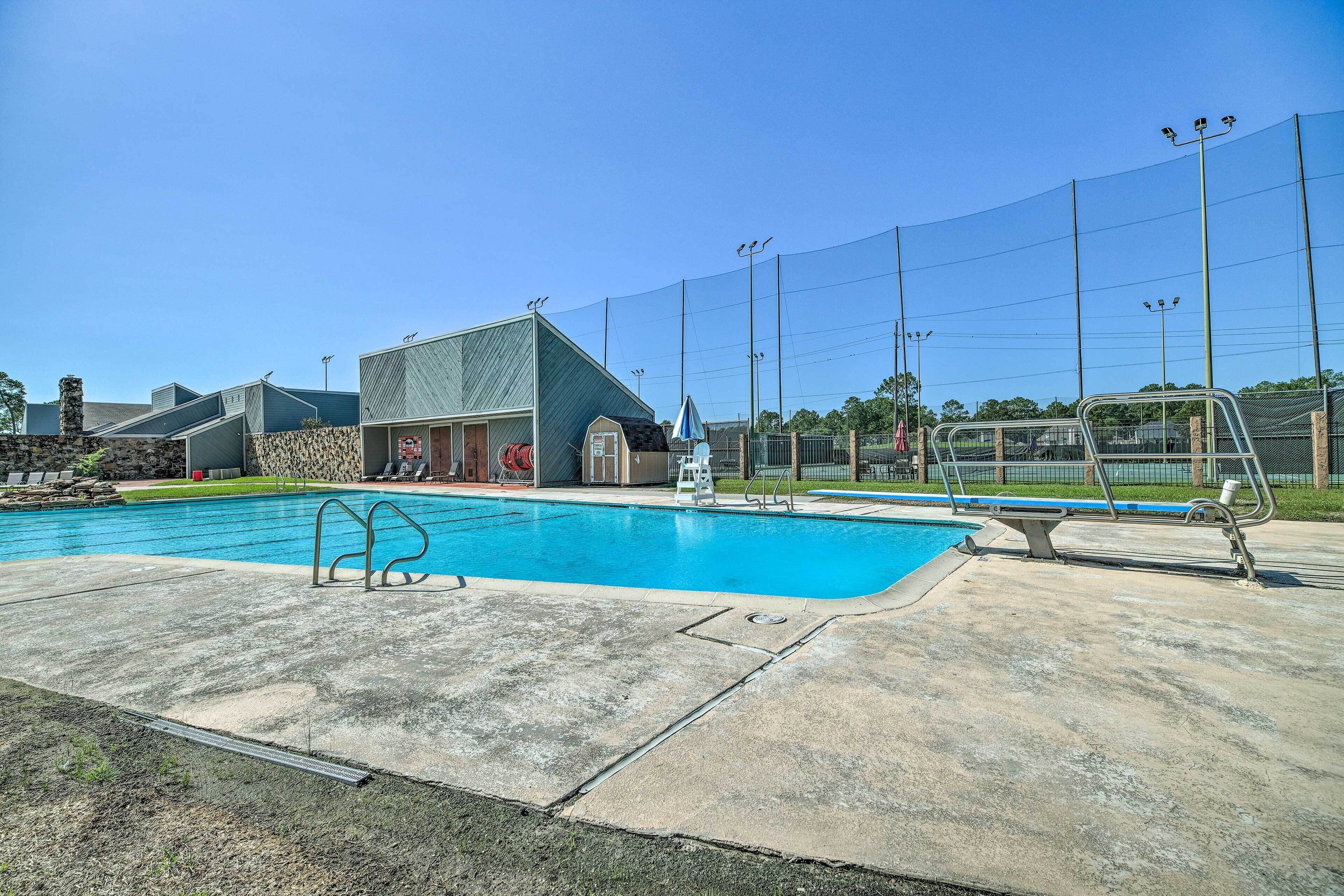 A swimming pool with a diving board, a lifeguard chair, and a fence.