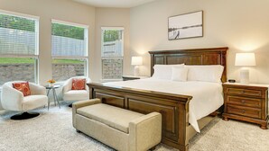 A bedroom with a large bed, two bedside tables, a chair, a bench, and a small table with a lamp. - Lake Conroe Home w/ Resort-style Perks & Patio (Montgomery)