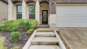 A two-story house with a front entrance, a garage, and a landscaped front yard. - Lake Conroe Home w/ Resort-style Perks & Patio (Montgomery)