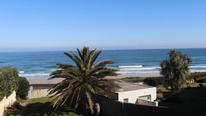 A coastal property with a view of the ocean, a white building, and palm trees. - hotel balcon de san bartolo (Barreiros)
