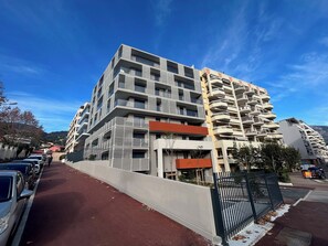 A multi-story residential building with balconies, a gated entrance, and a red pavement. - Kosmic 702 by Avecoeur (Roquebrune-Cap-Martin)