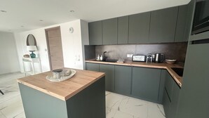 Eine moderne Küche mit dunkelgrauen Schränken, einer Holz Arbeitsplatte und einem Boden aus Marmorfliesen.