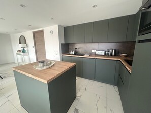 A modern kitchen with dark grey cabinets, a wooden countertop, and a marble-tiled floor. - Kosmic 702 by Avecoeur (Roquebrune-Cap-Martin)