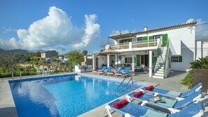 Une piscine avec des chaises longues et un bâtiment doté d’un balcon.
