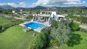 Une grande maison avec une piscine, un patio couvert et une vue sur les montagnes.