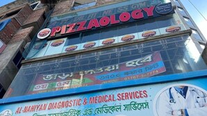 Rakennuksessa on kyltti, jossa lukee »Pizzaology» ja »Al-Nahiyanin diagnostiset ja lääketieteelliset palvelut».