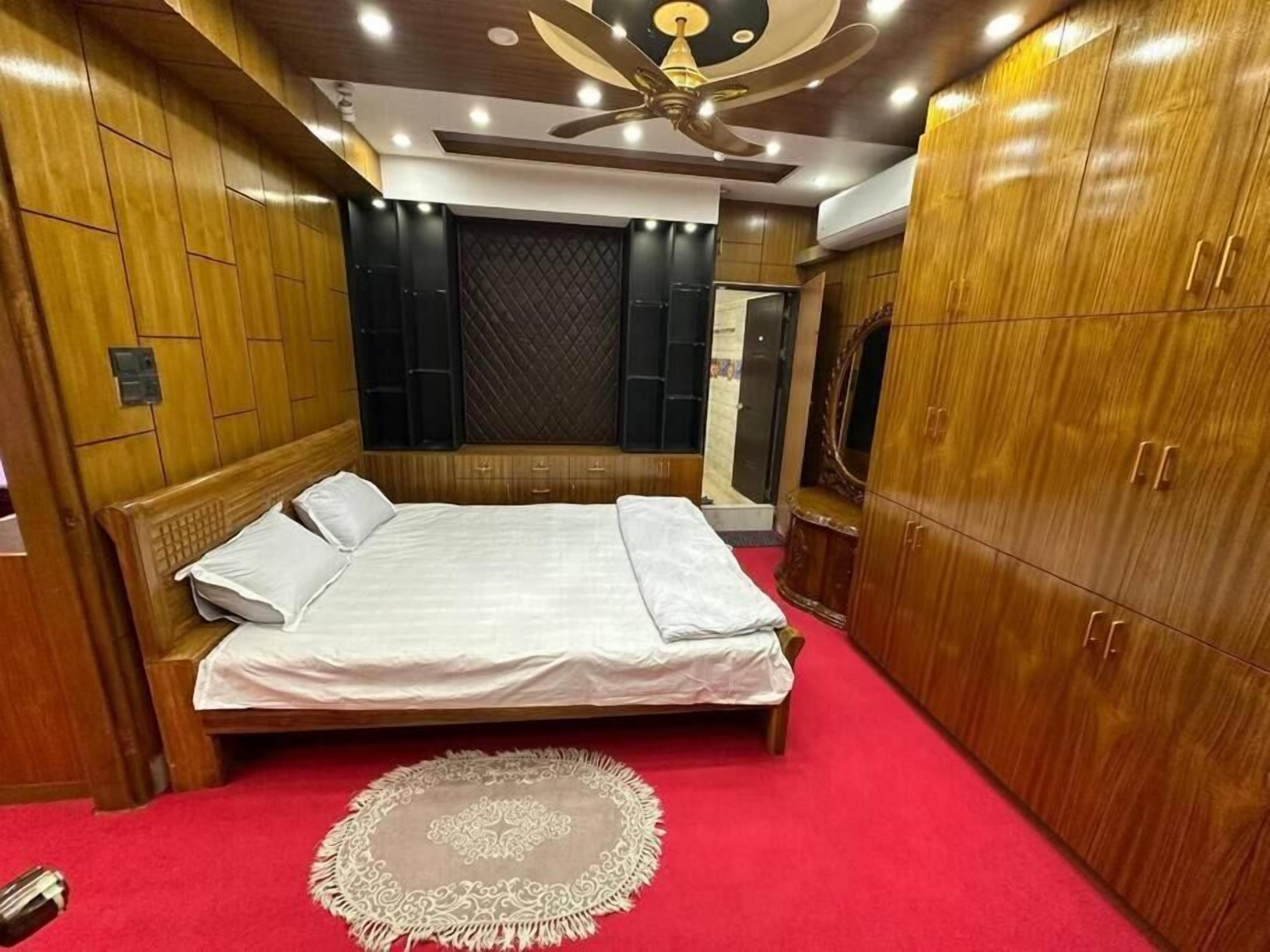 A bedroom with a bed, wardrobe, and ceiling fan.