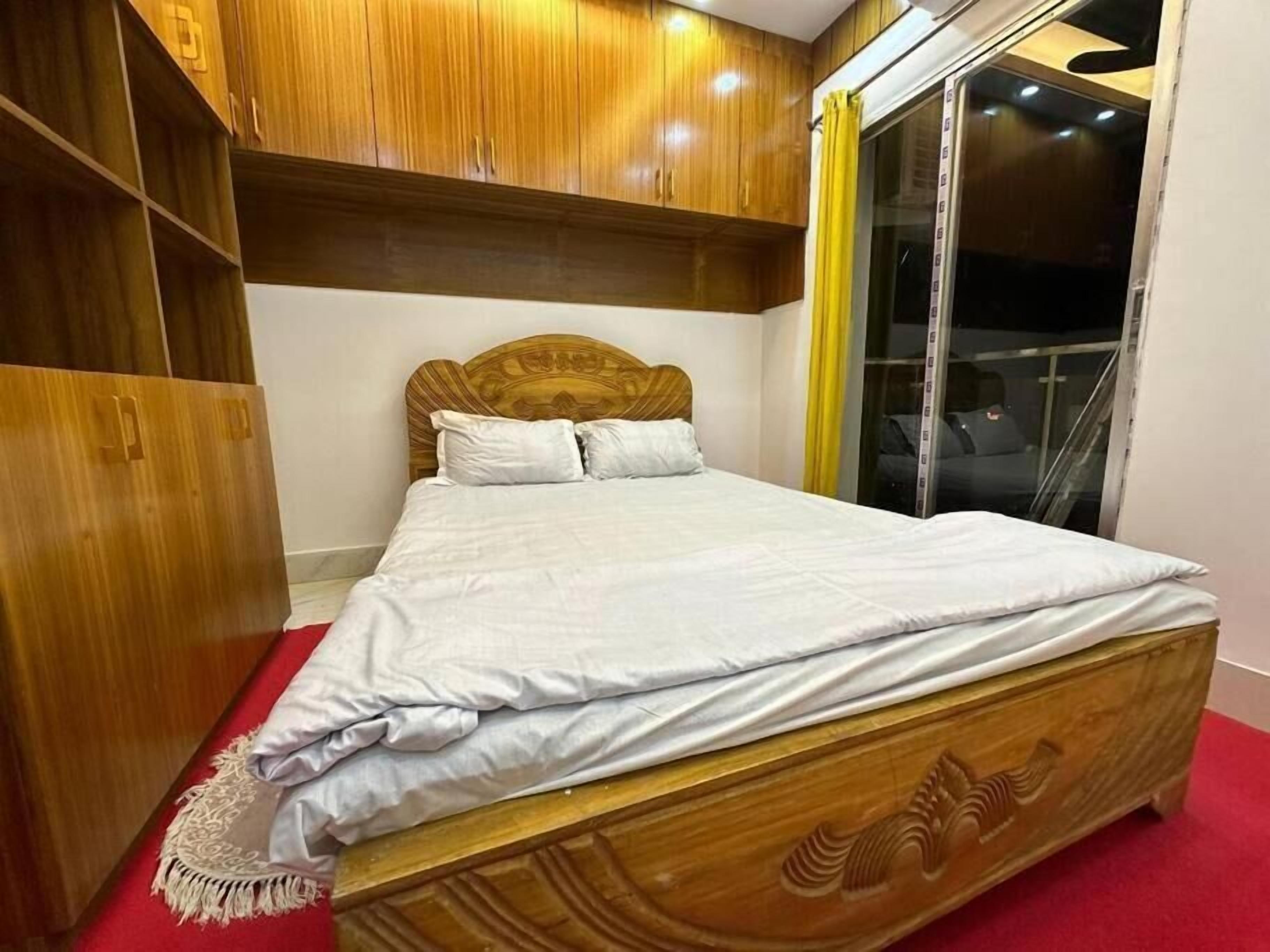A bedroom with a wooden bed frame, a large wardrobe, and a sliding glass door.