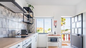 Een moderne keuken met een magnetron, koffiezetapparaat en een kleine plant op het aanrecht.