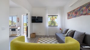 Een moderne woonkamer met een bank, een televisie en een geruit tapijt.