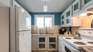 A kitchen with white appliances, a window, and teal walls.