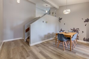 Een moderne eetruimte met een houten tafel en stoelen, een trap en een muur met bladstickers.