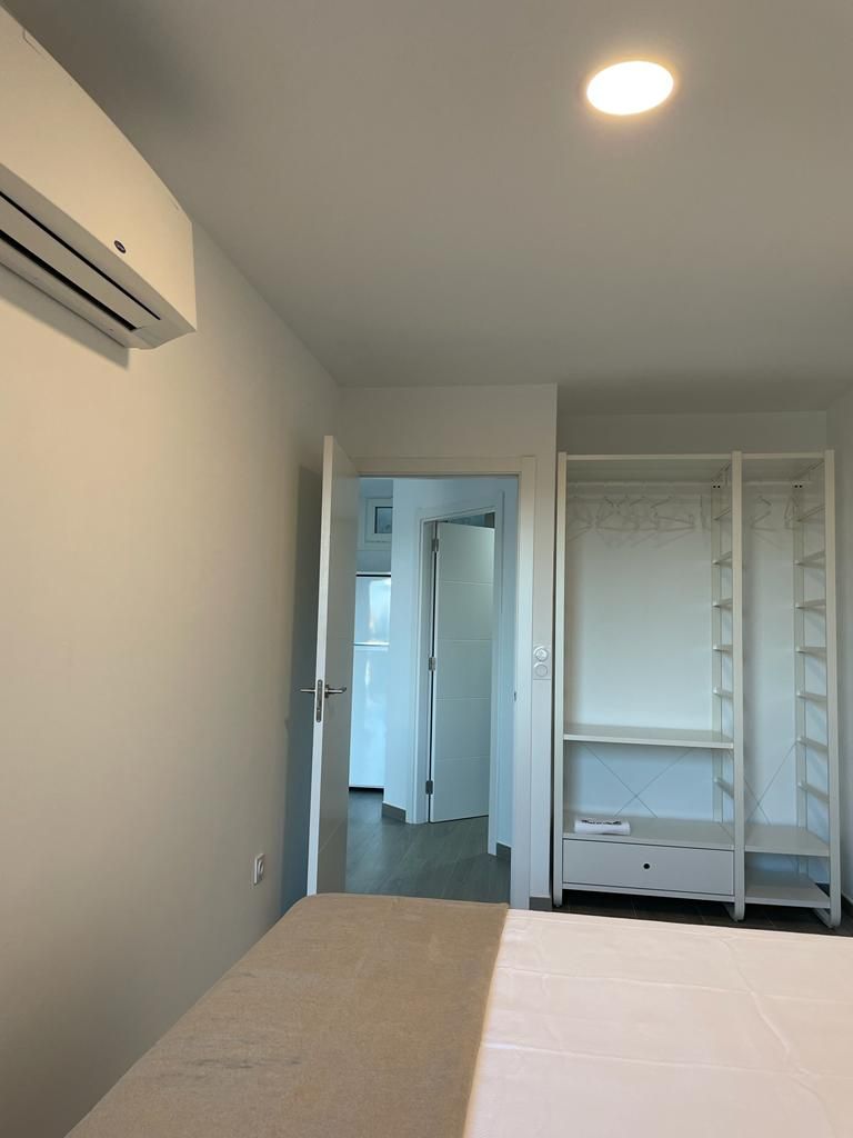 Ein Schlafzimmer mit Bett, Klimaanlage, Kleiderschrank und einer Tür zu einem anderen Raum.