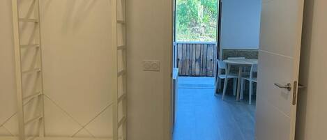 Una habitación con una cama, un armario y una puerta abierta que da a un espacio exterior con una mesa y sillas.