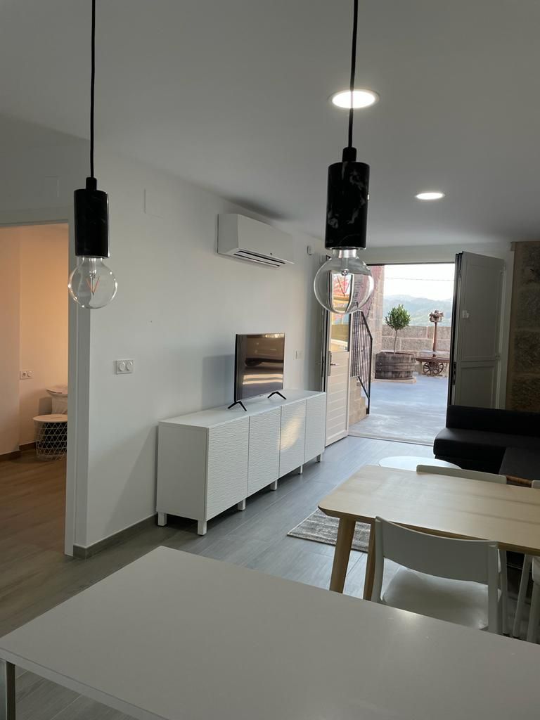 A modern kitchen with white cabinetry, a dining area with a table and chairs, and pendant lights.