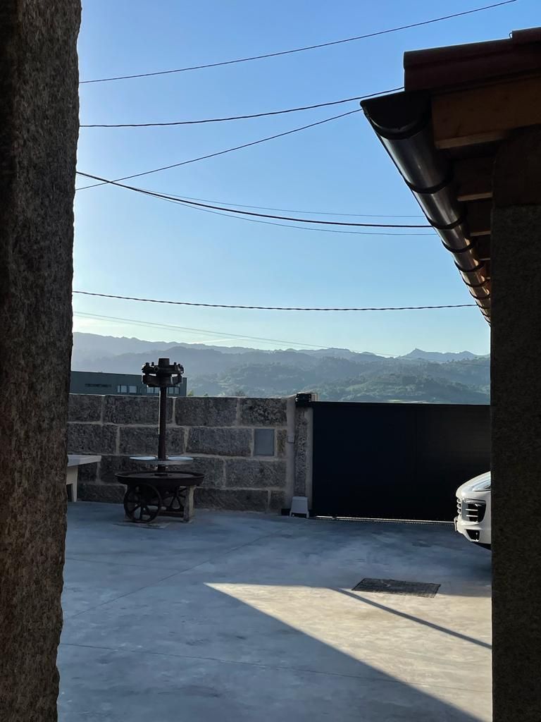 A rooftop patio with a stone wall, a table, and a car parked nearby.