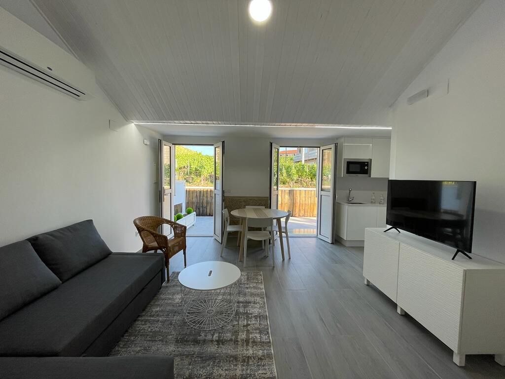 Una sala moderna con un sofá, una mesa de comedor y un televisor sobre un mueble.