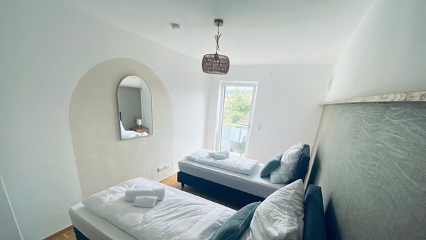 Een slaapkamer met twee bedden, een grote spiegel en een raam.