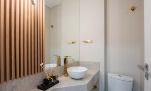 A modern bathroom with a wooden panel wall, a white sink with a gold faucet, and a toilet. - Apt w/ Barbecue Grill 500m From the Beach Tdf0302 (Itapema)